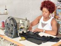 A tailor carefully pinning the hem of a woman's trousers, illustrating a crucial tailoring basic for affordable clothes.