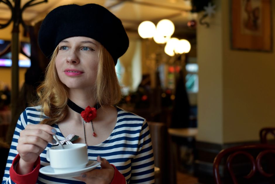 A woman wearing a classic navy and white Breton stripe top and straight-leg jeans, enjoying coffee at a café, capturing effortless style.