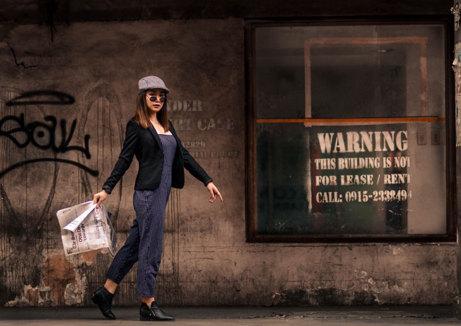 A stylish woman walking on a city street, dressed in a relaxed fit white linen shirt and wide-leg beige trousers, carrying a straw tote bag, embodying French-inspired summer style for humid cities.