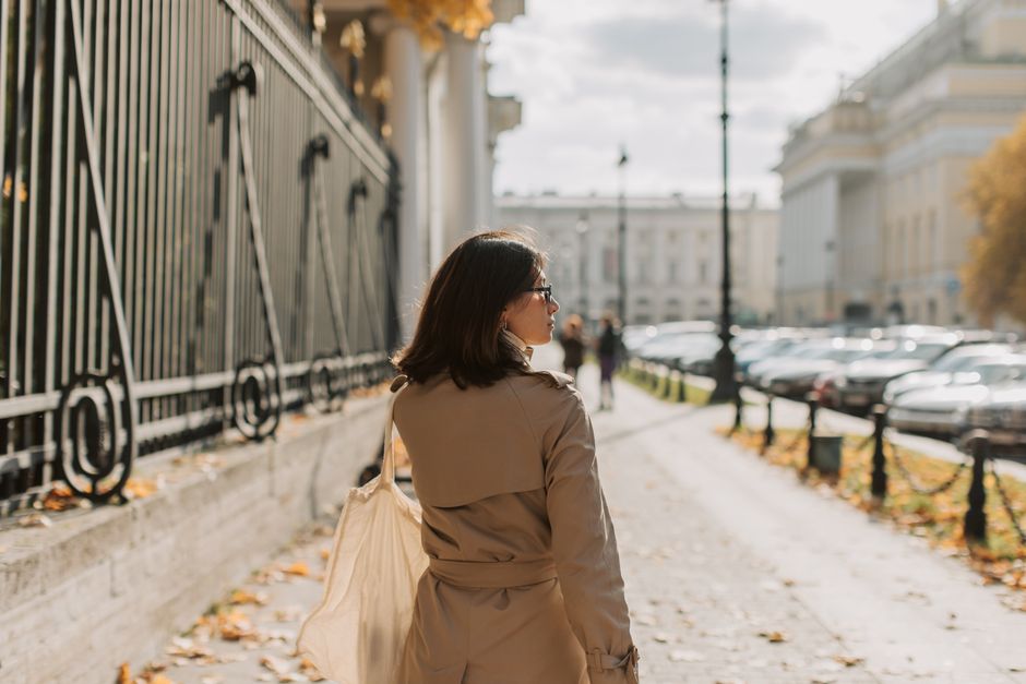 A stylish woman in a classic beige trench coat walks confidently down a European city street, embodying French elegance.