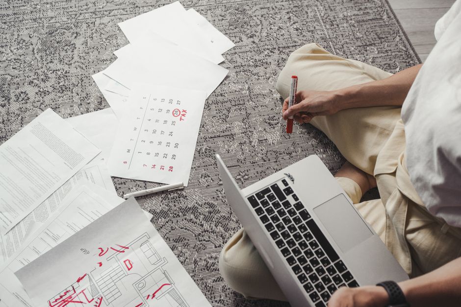 Woman smiling while reviewing her digital calendar and making notes on a laptop, demonstrating lifestyle planning.