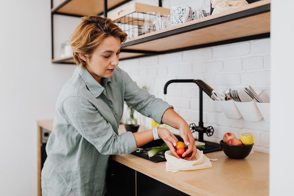 A woman quickly tossing a salad with fresh vegetables, feta, and canned chickpeas in a kitchen, showing the ease of preparing a Mediterranean-inspired meal.