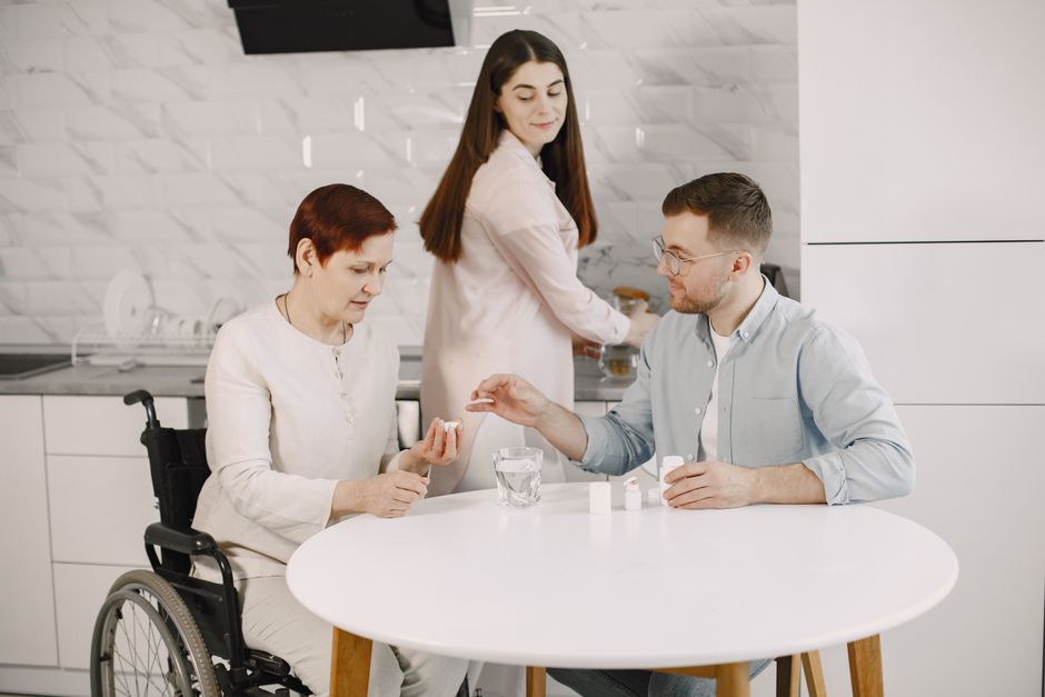 A host smiling and relaxed while guests help clear plates in a casual kitchen, illustrating the ease of delegating tasks during a simple dinner party.
