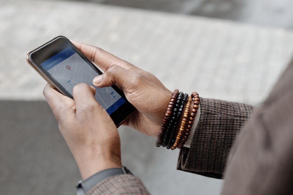 A woman holding a smartphone displaying a map application, looking slightly stressed while navigating a busy, narrow street in an old European city.