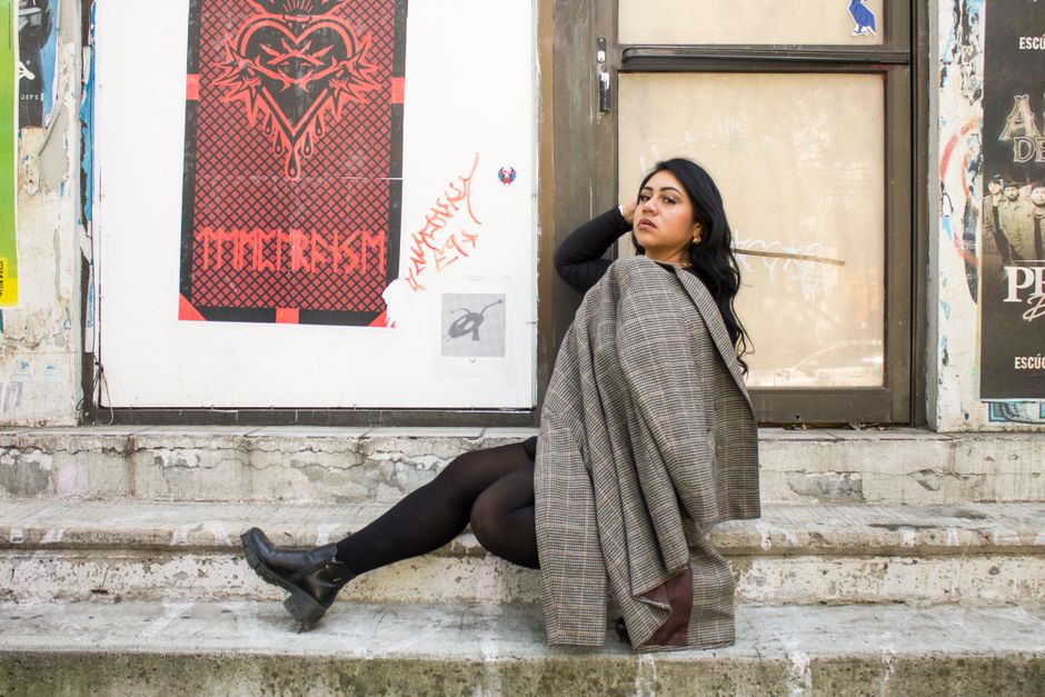 A stylish woman in a vibrant tweed statement jacket walking confidently down a busy city street, showcasing urban professional style.